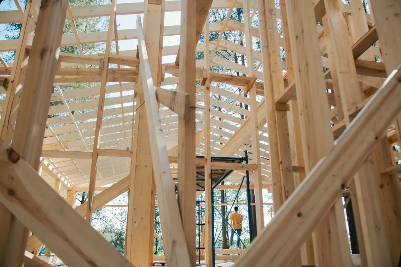 New timber house framing seen from inside, with the wall studs and roof structure standing open to the sky.
