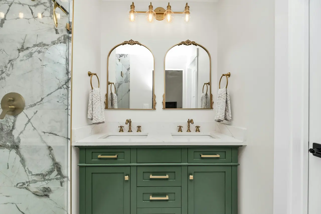 A double vanity in deep green with brass tapware