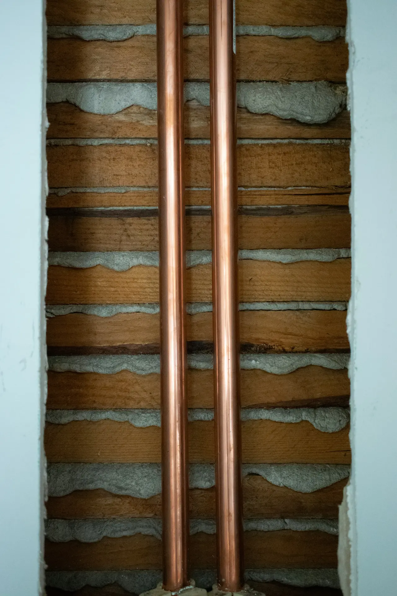 Two new copper pipes running up an opened wall
